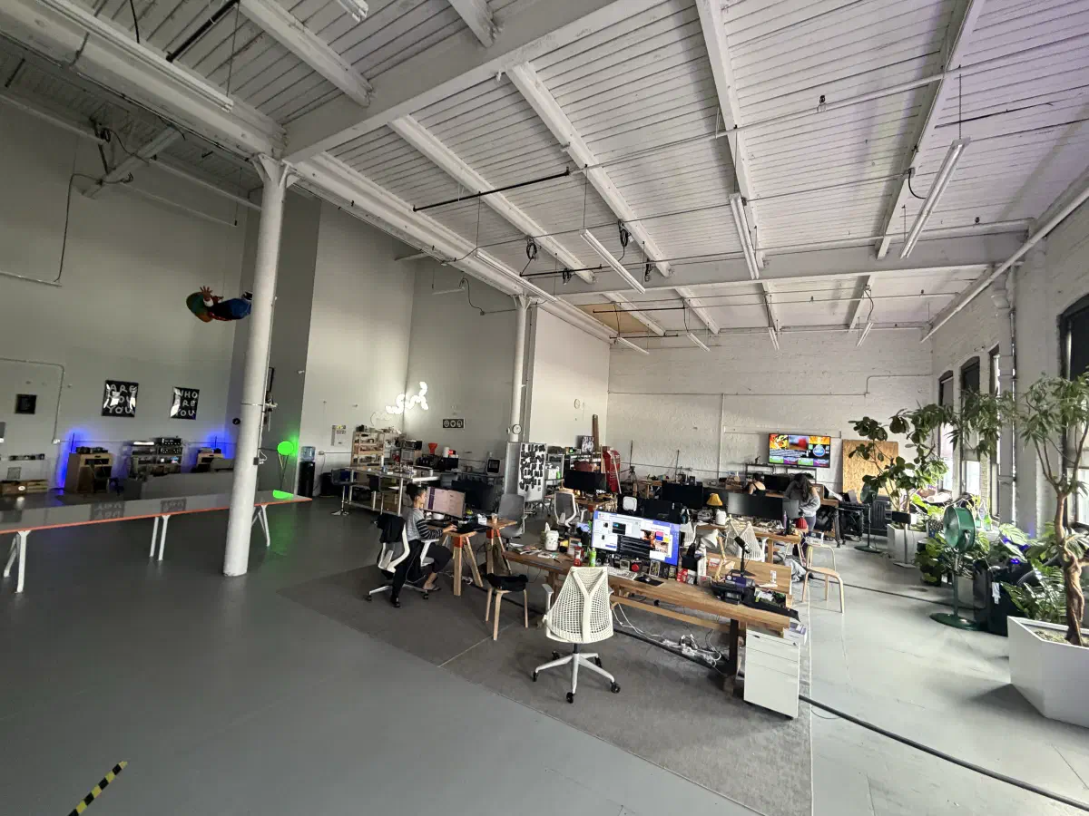 Wide view of people working among desks, plants, and equipment in the 2389 Research office.